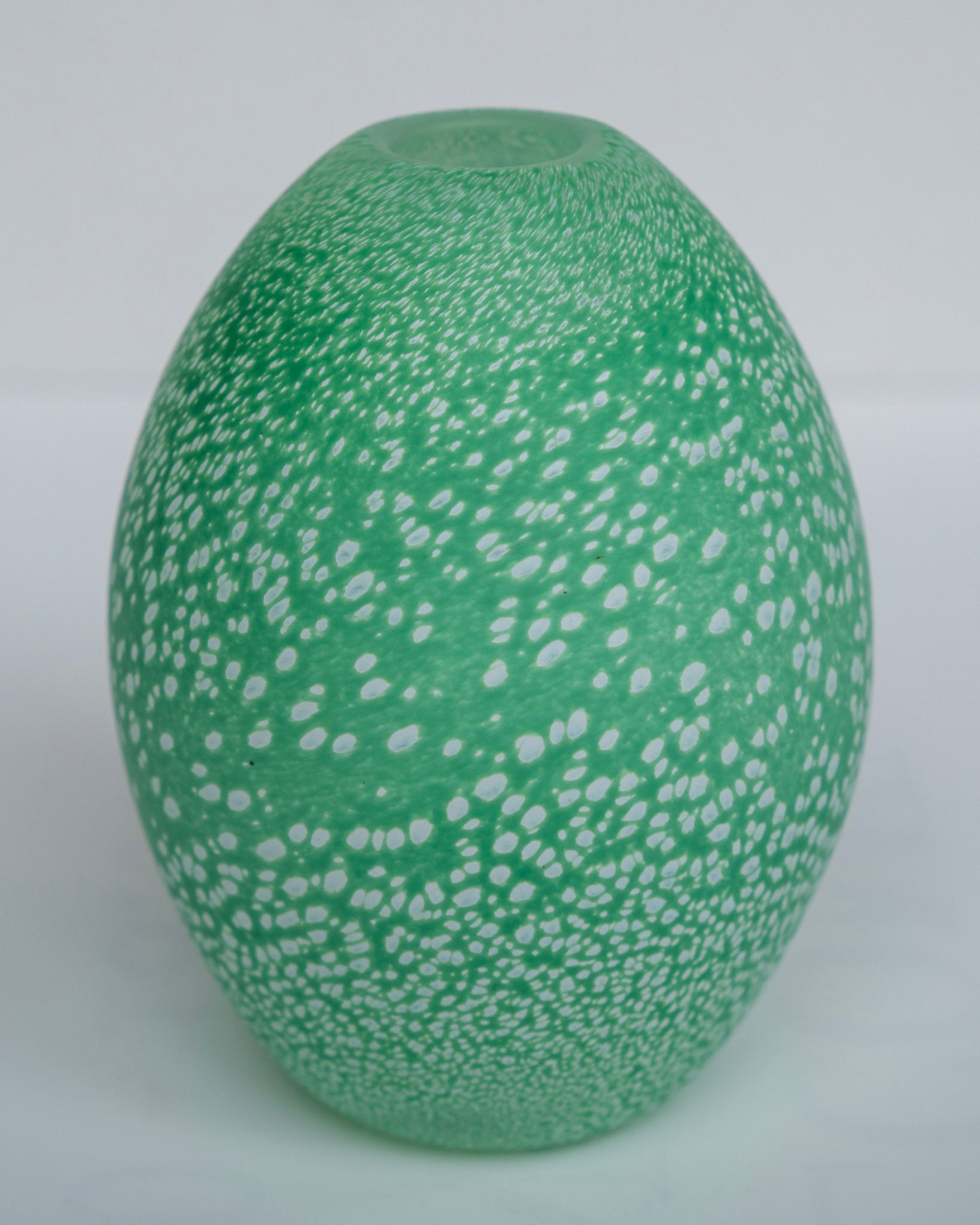 Grønn eggevase i eggform med hvite prikker og blank overflate.