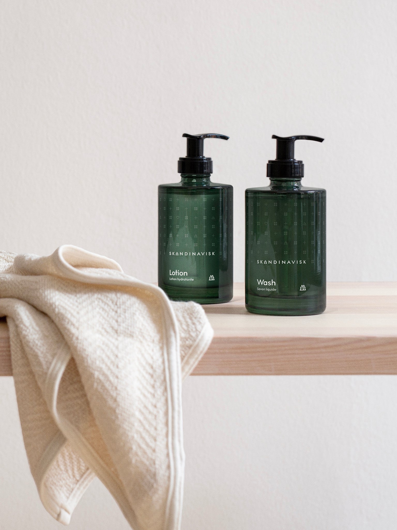 To grønne pumpeflasker, lotion og vask, ved håndkle