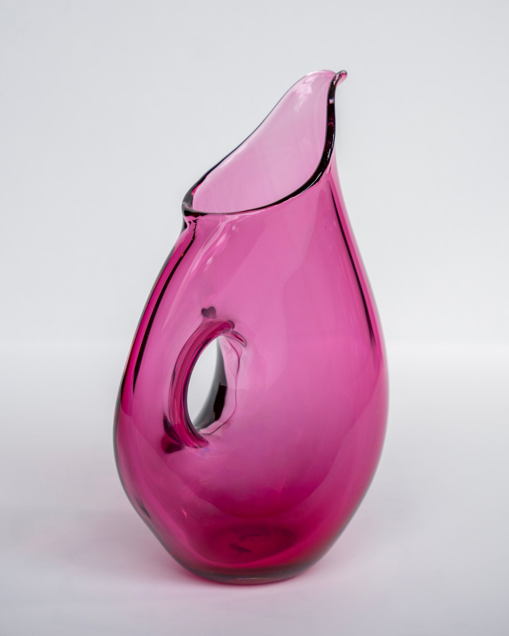 Rosa fløtemugge i glass med blank svart kant og dråpeformet hank