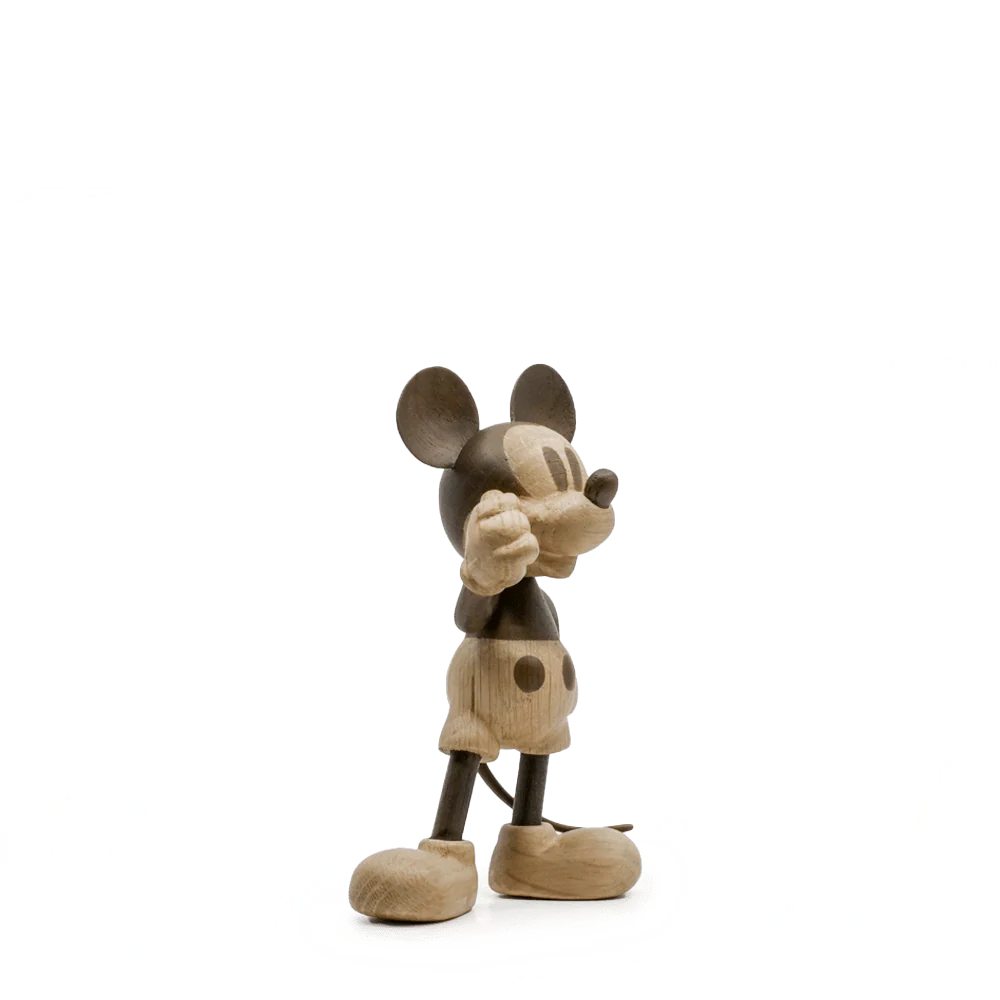 Liten Disney x Mickey Mouse figur i lyst tre, trekvart sidevisning med armer løftet