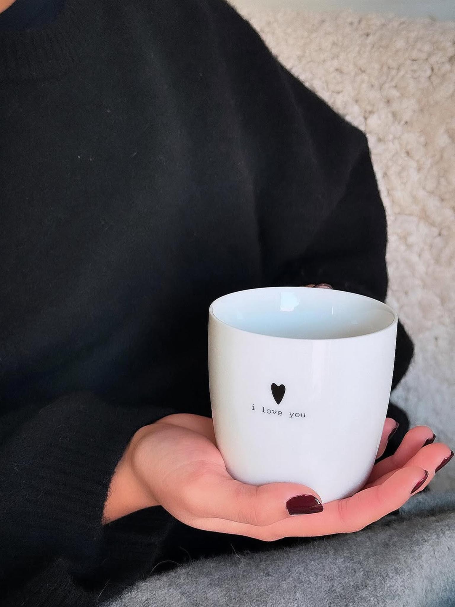 Hvit krus holdt i hånd, med hjerte og «I love you»