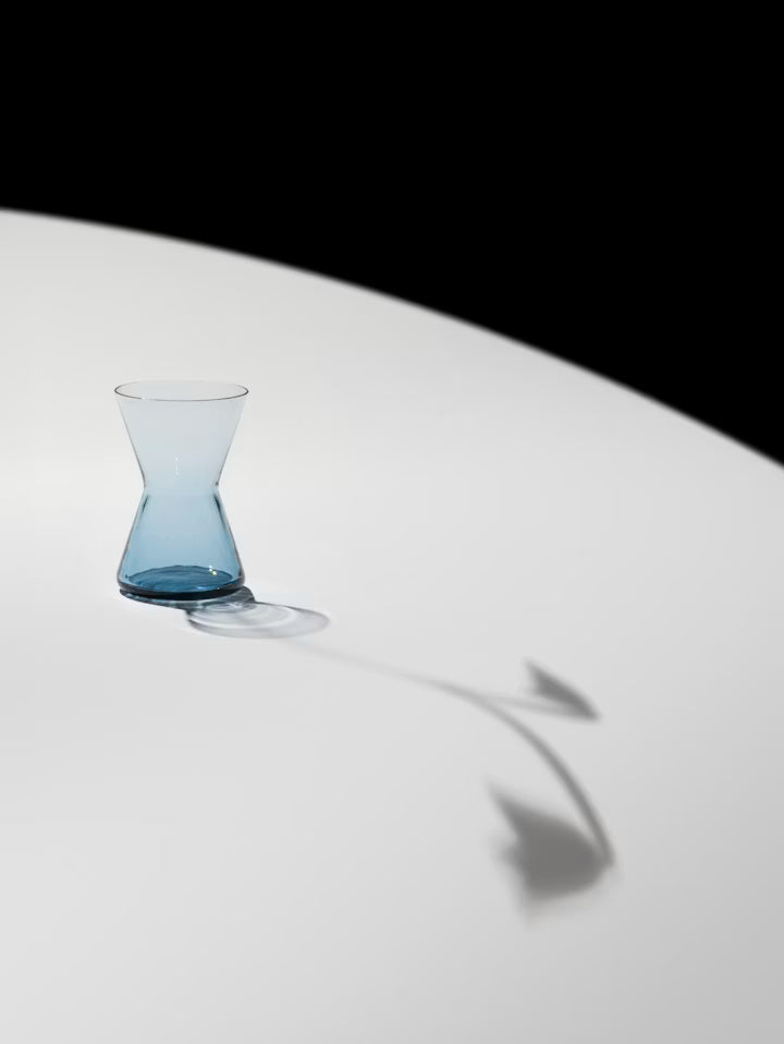 Minivase i klart blått glass med smal hals og avrundet bunn sett fra siden