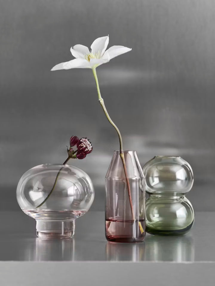 Minivase i klart glas med rød tone, med blomst i centrum