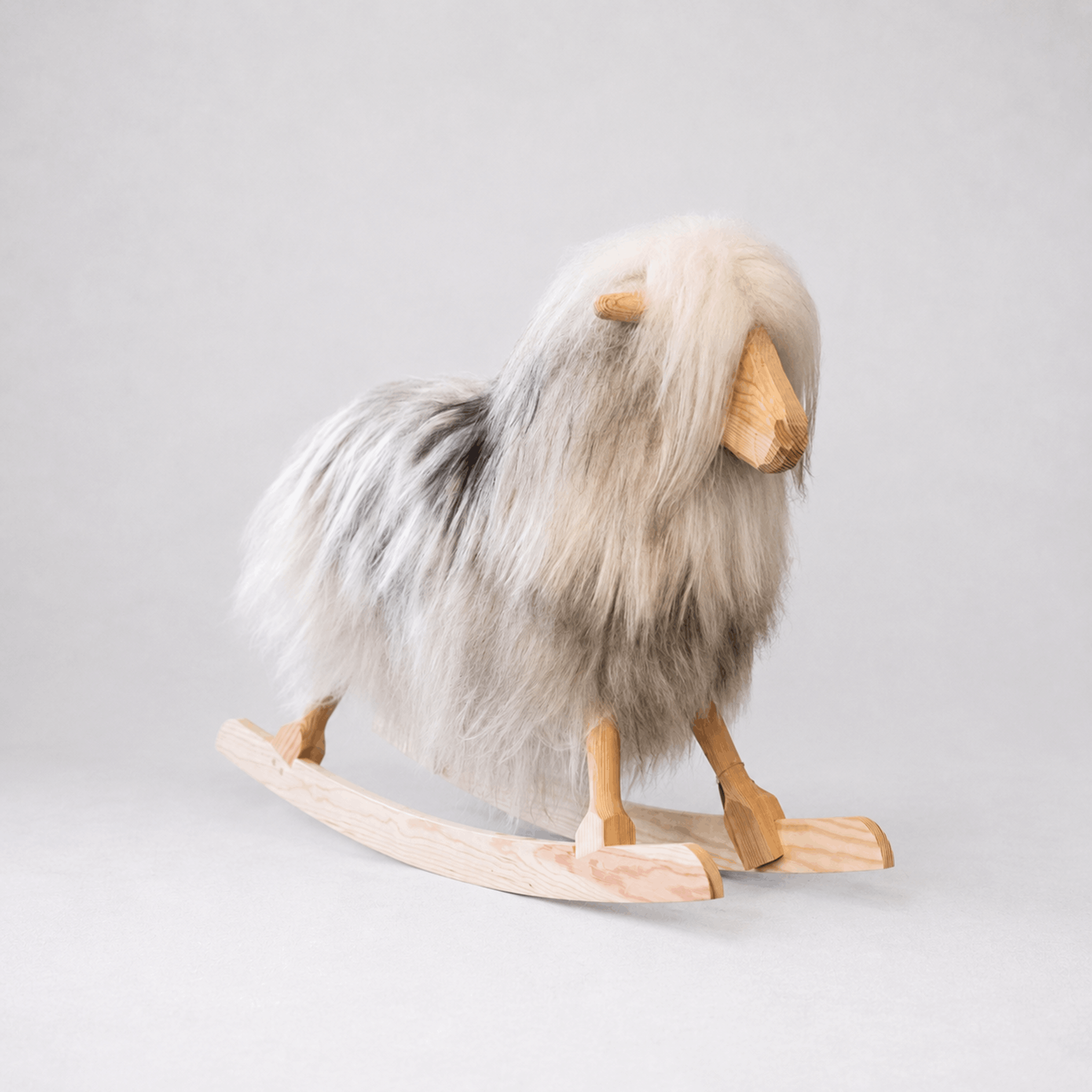 Gyngende hest i plysj, grå og beige, med tre ben og ski-løpere