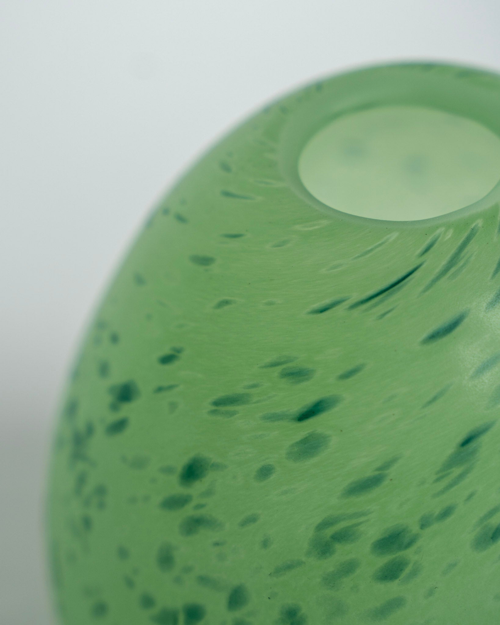 Grønn eggevase med lys åpning og prikkete overflate
