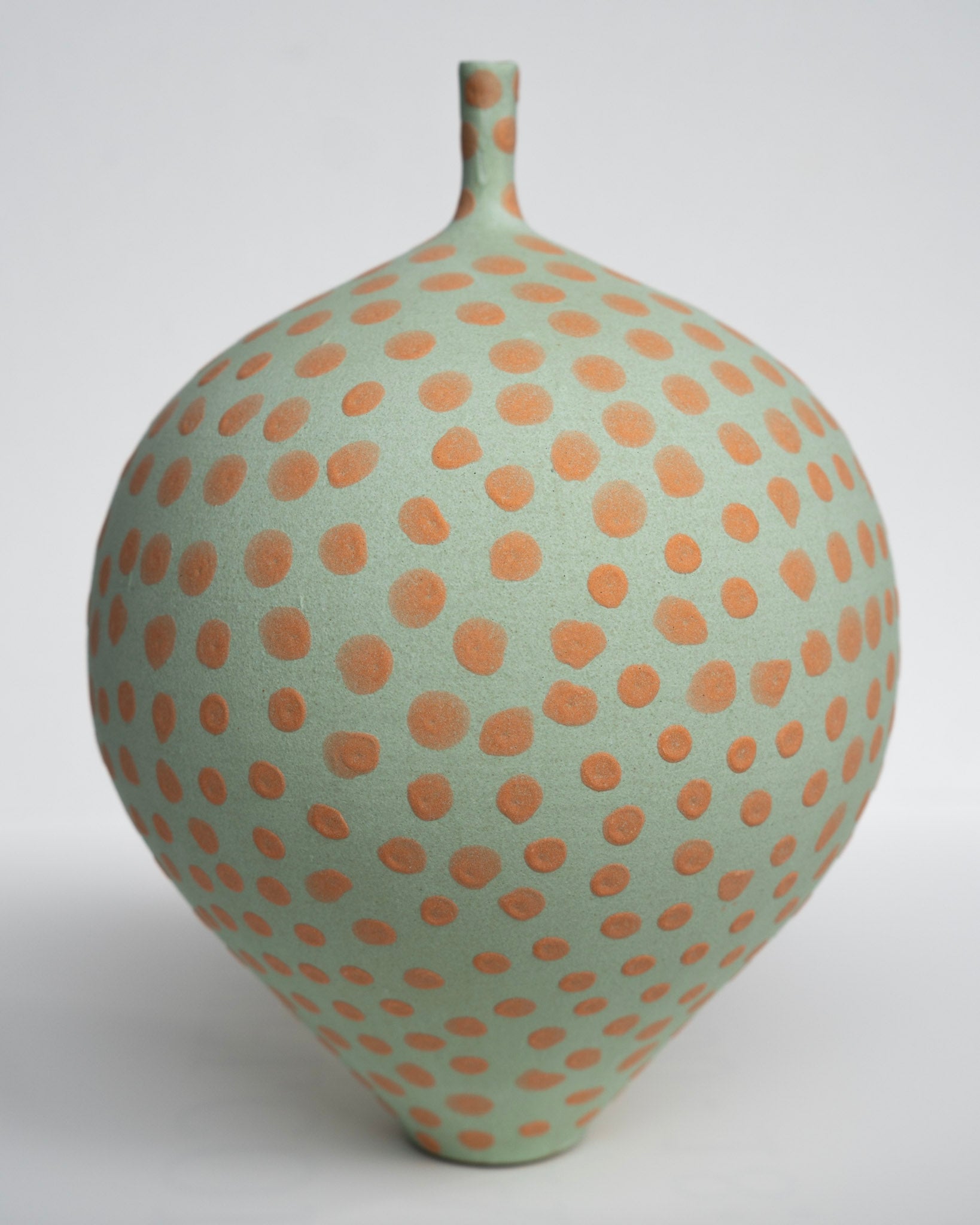 Keramisk vase i lysegrøn med orange prikker, rund mave og smal hals