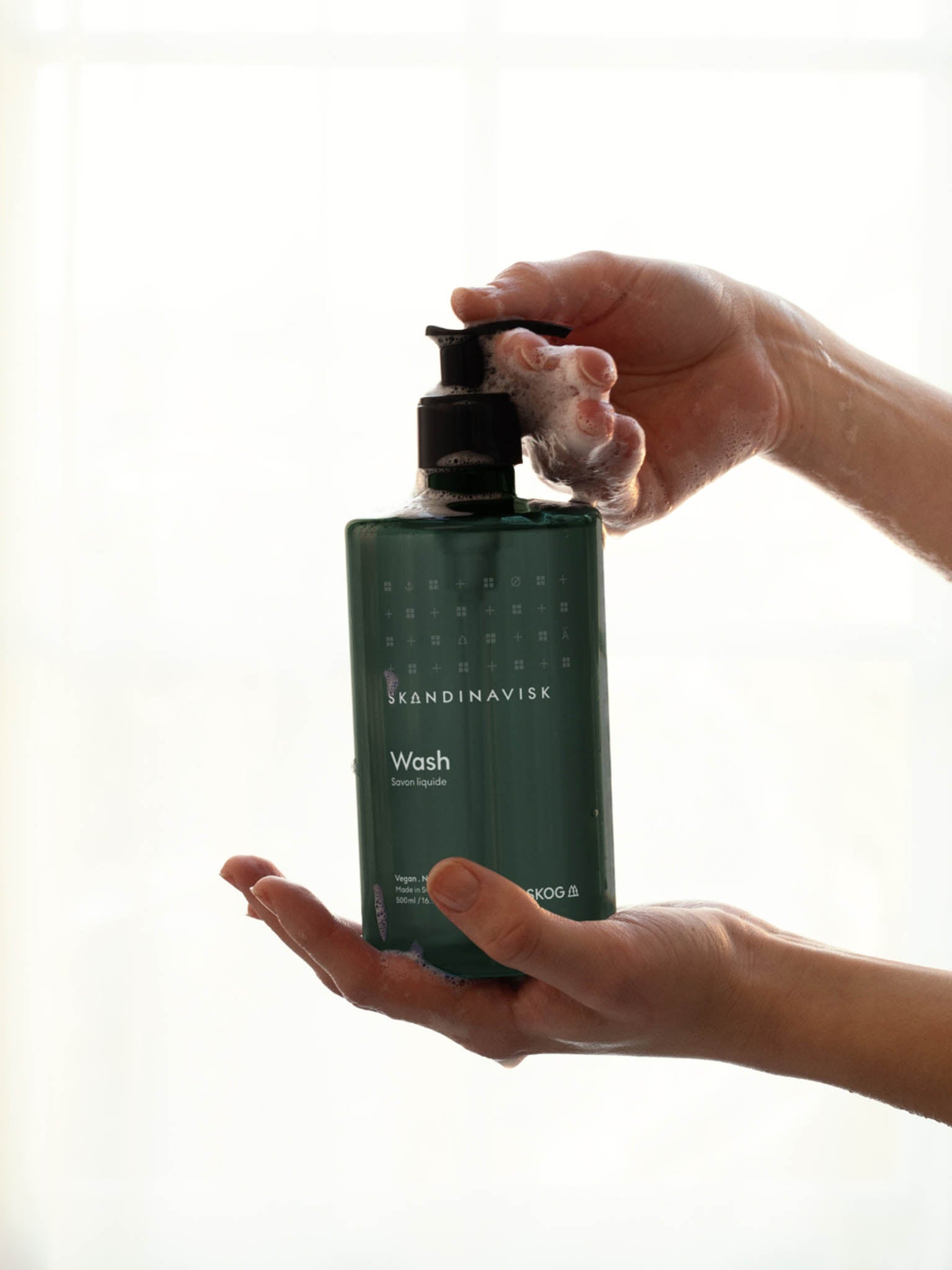 Hender som trykker på pumpe fra grønn såpevaskflaske.