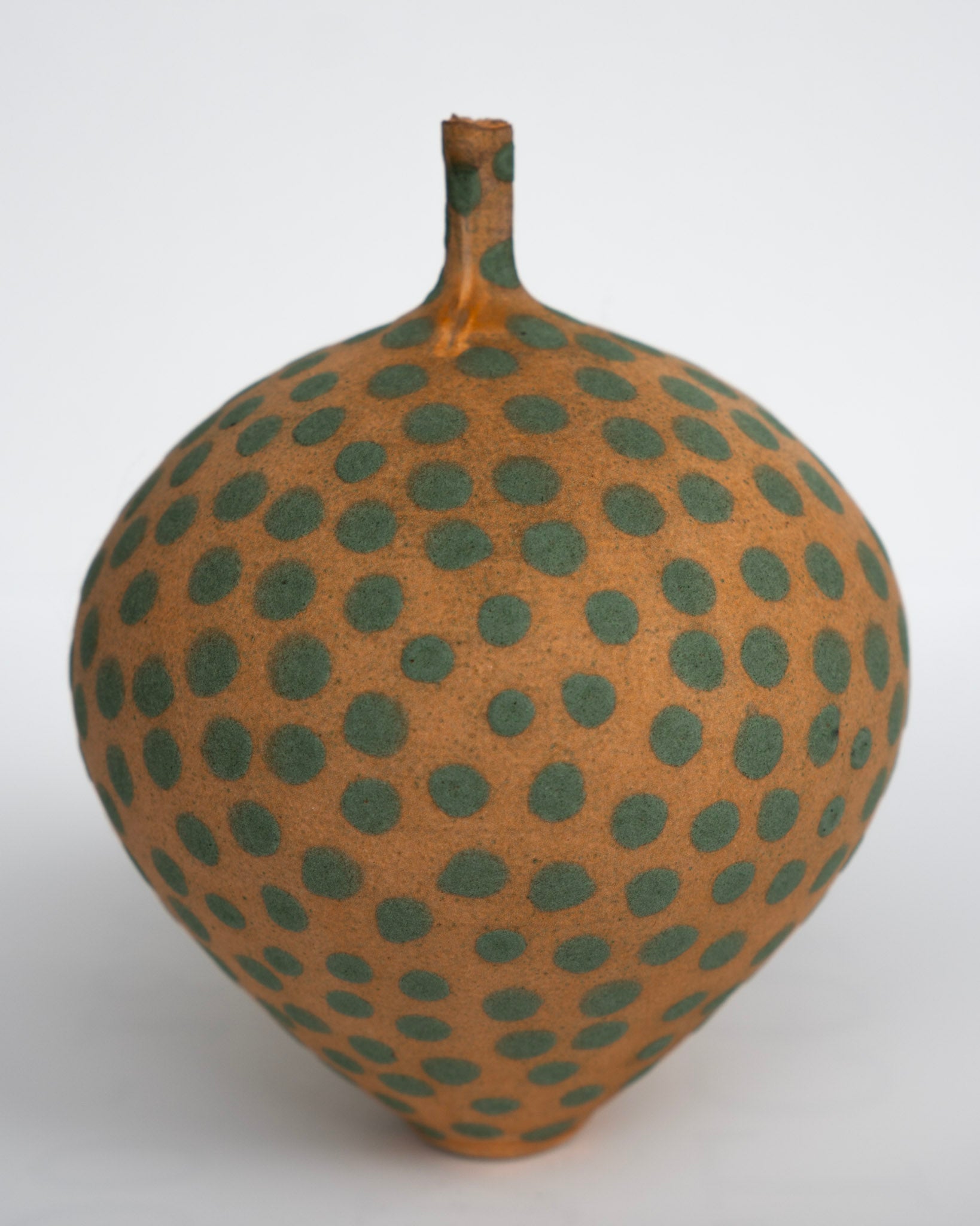 Keramisk vase med oransje bunn og grønne prikker, rund kropp og smal hals