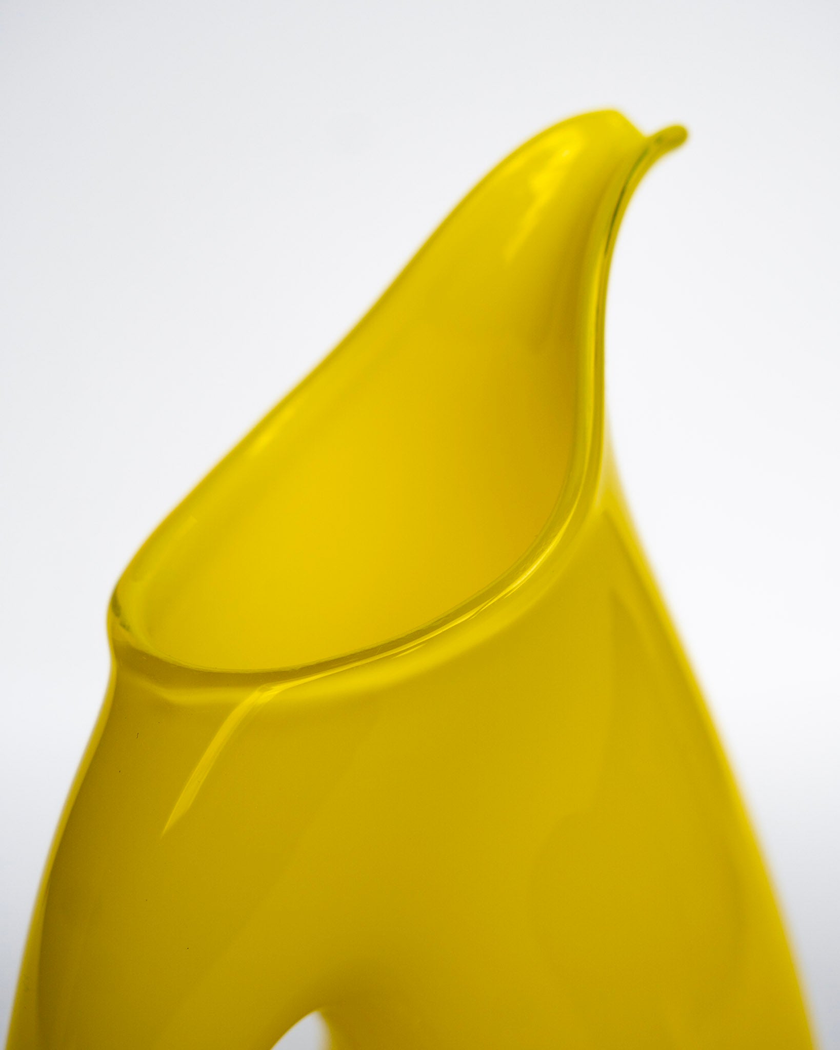 Fløtemugge i knallgul plast med lang tut og avrundet kropp.