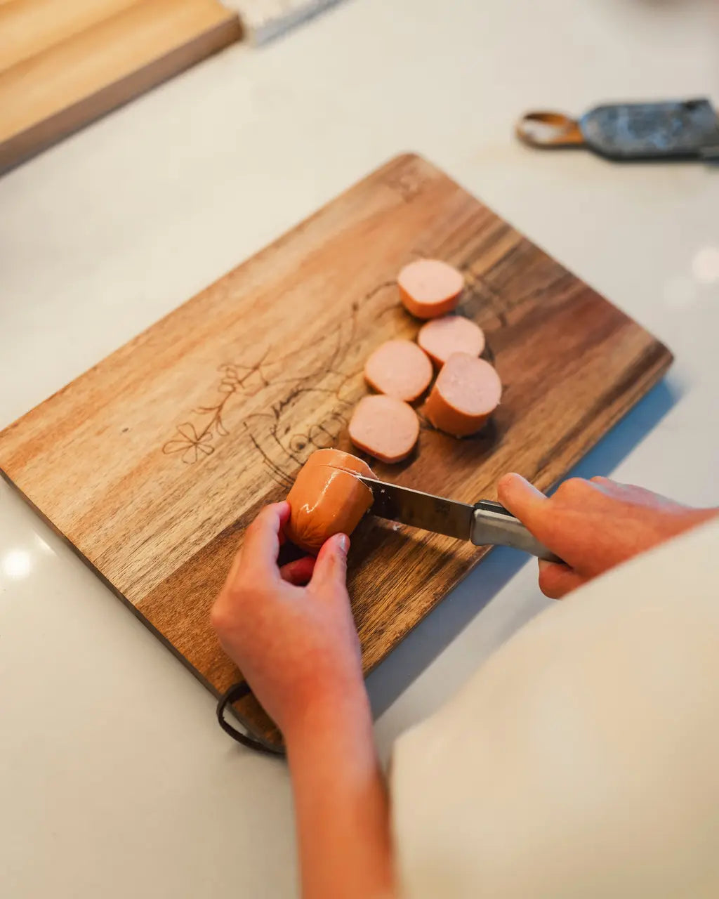 Kjøkkenkniv med rustfritt blad for skjæring, med grå filt-slire og brun lærreim.