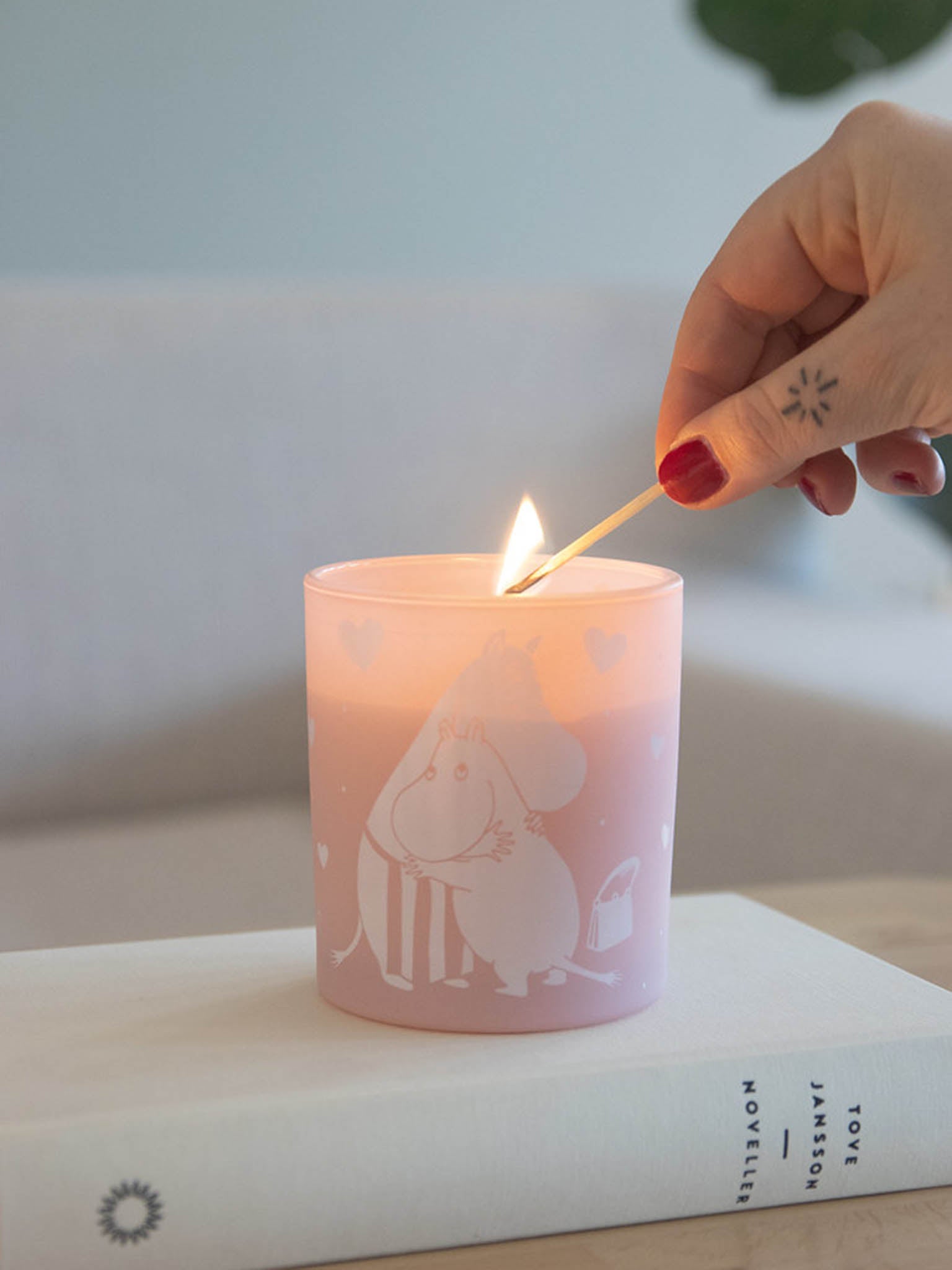 Rosa duftlys i glass med Moomin-illustrasjon, tent veke