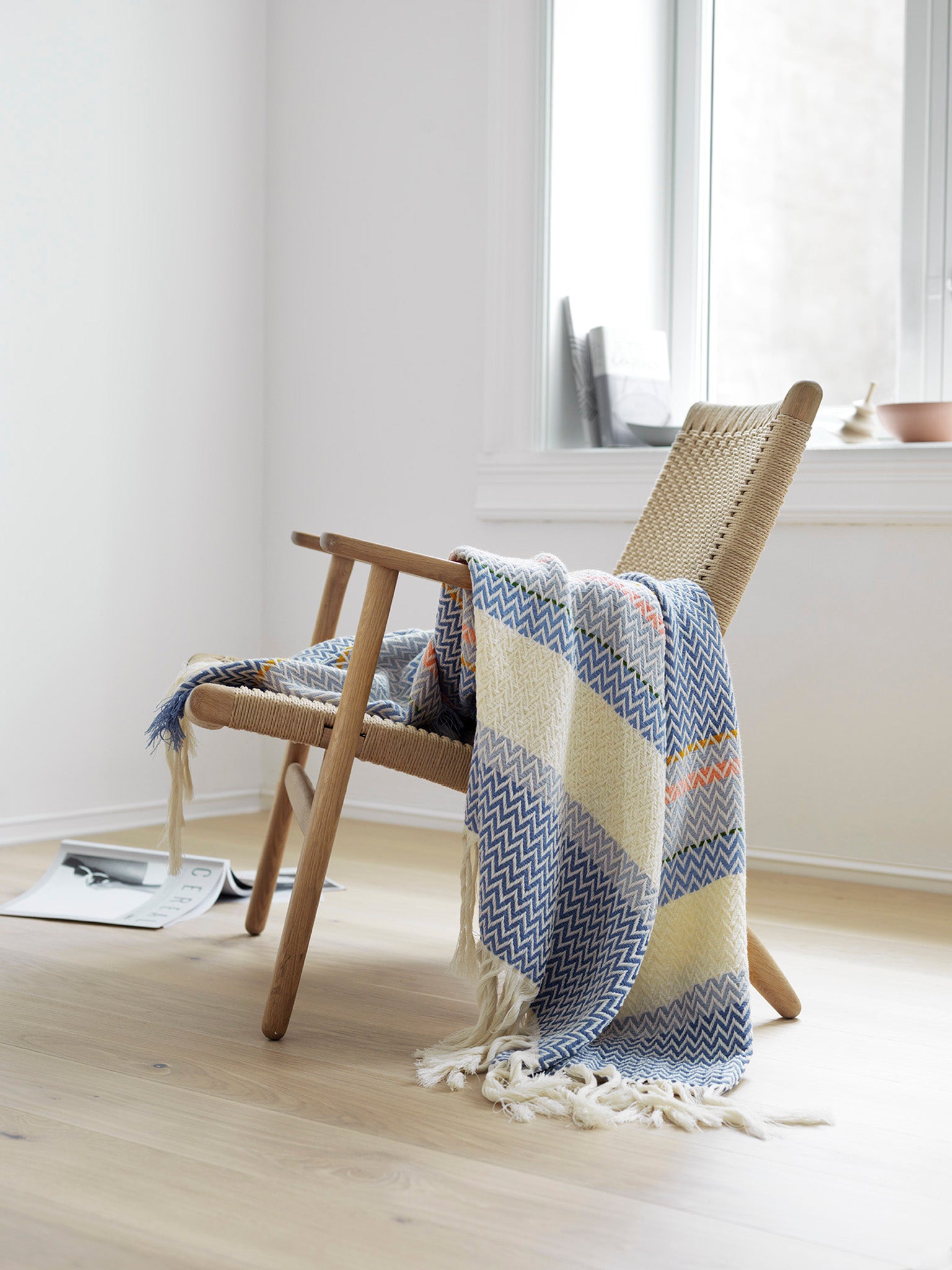 Bunadspledd med sikksakkmønster i blått og beige, frynser i kantene.